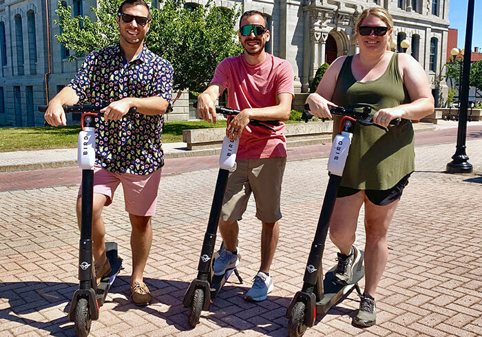 Mayor William Barlow, from left, Matt Fragale, fleet manager of Bird scooters for Oswego, and an unidentified scooter user in front of Oswego City Hall in July.